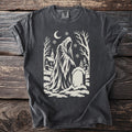 Pepper gray t-shirt with a cream folk-cut print: the hooded Ghost of Christmas Yet to Come points one finger at a snowy grave.