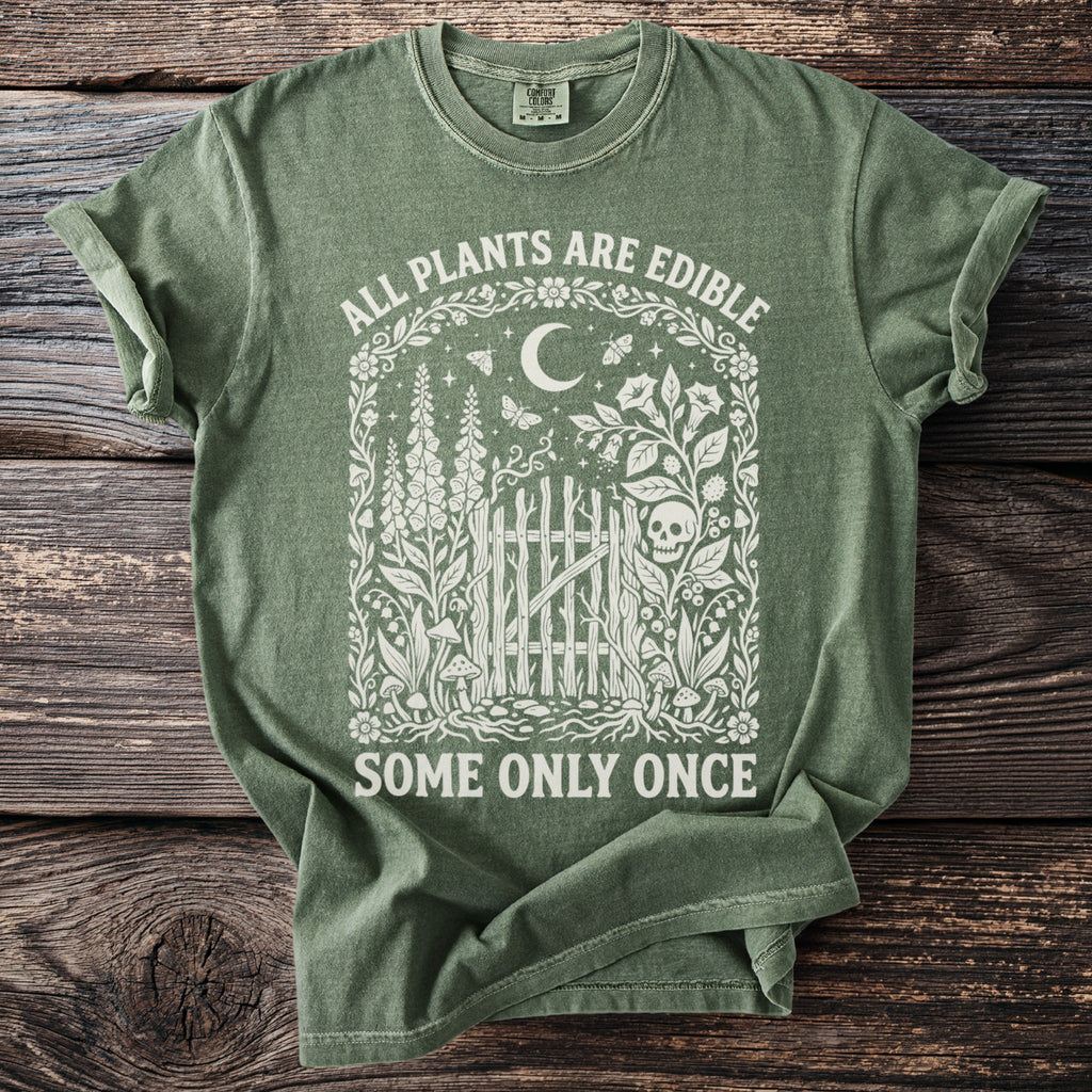 Green t-shirt with "ALL PLANTS ARE EDIBLE SOME ONLY ONCE" text and floral skull design.