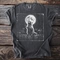 Graphic t-shirt with raccoon howling at full moon over trash bins and fence.