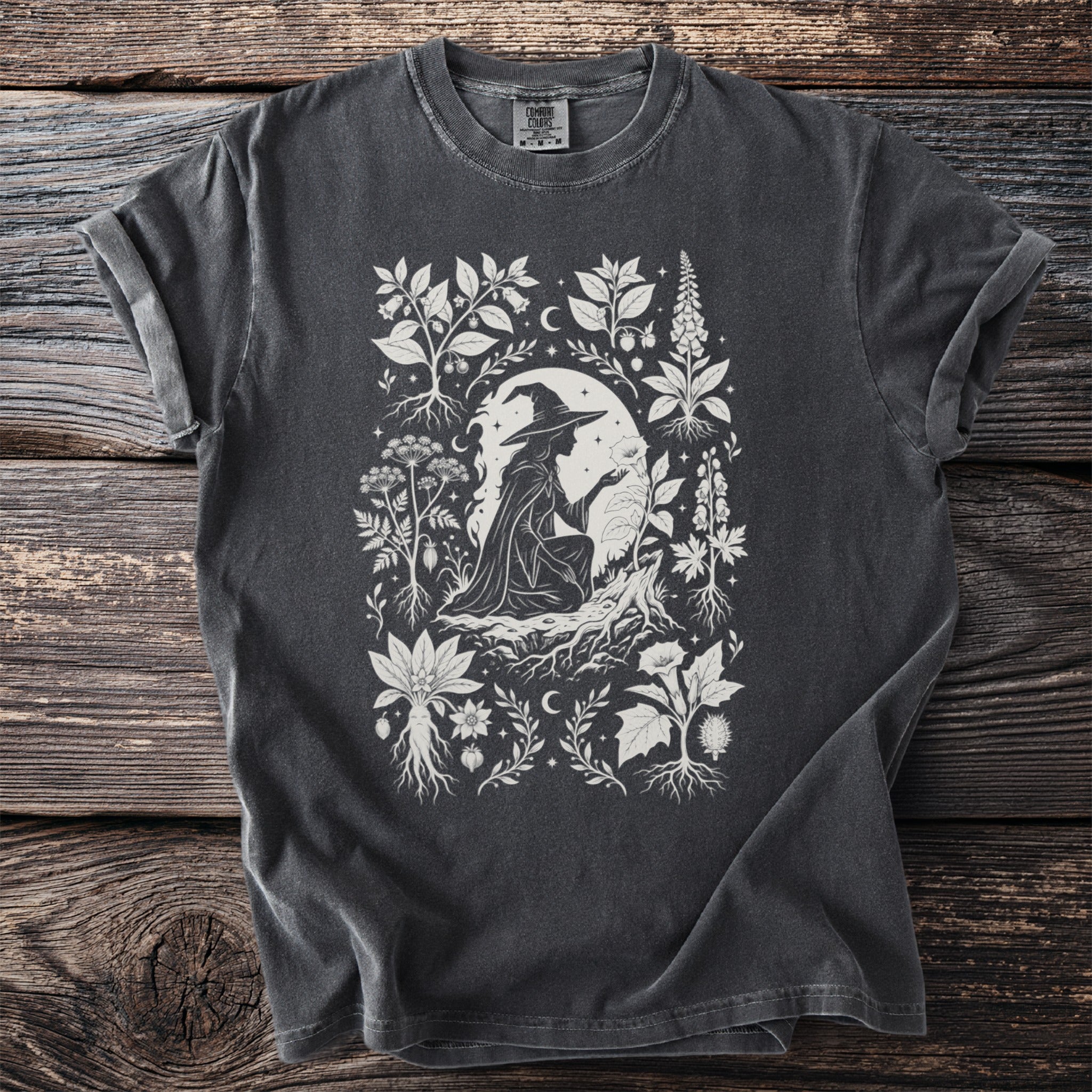 Charcoal t-shirt with a white linework design of a witch and mystical plants.