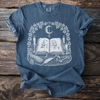 T-shirt with occult graphic: open book, candles, moon, quill, inkwell, key, and herbs.