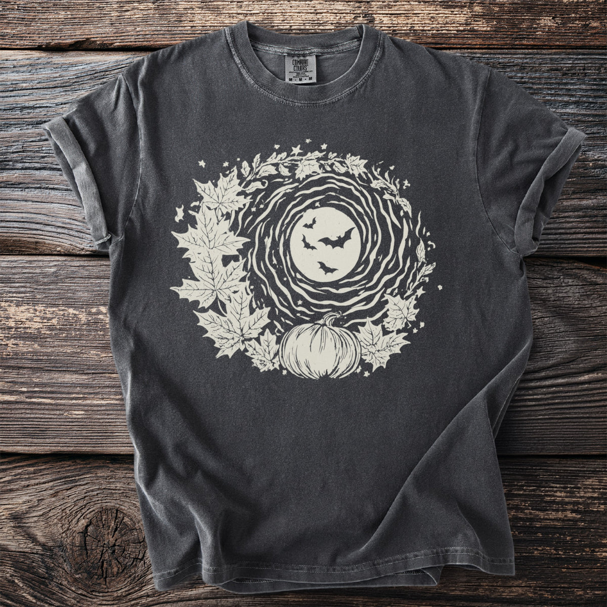 Dark t-shirt with a round graphic of a moon, bats, leaves, and a pumpkin.