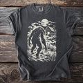 Bigfoot silhouette wading in a misty swamp in front of a cabin under the moon.