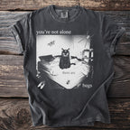 Black t-shirt with graphic of cat on a bed with butterflies, spiders, and bugs, "you're not alone there are bugs."