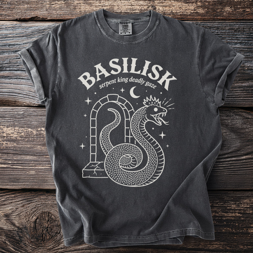 Dark grey t-shirt with white "BASILISK serpent king deadly gaze" text and snake graphic.