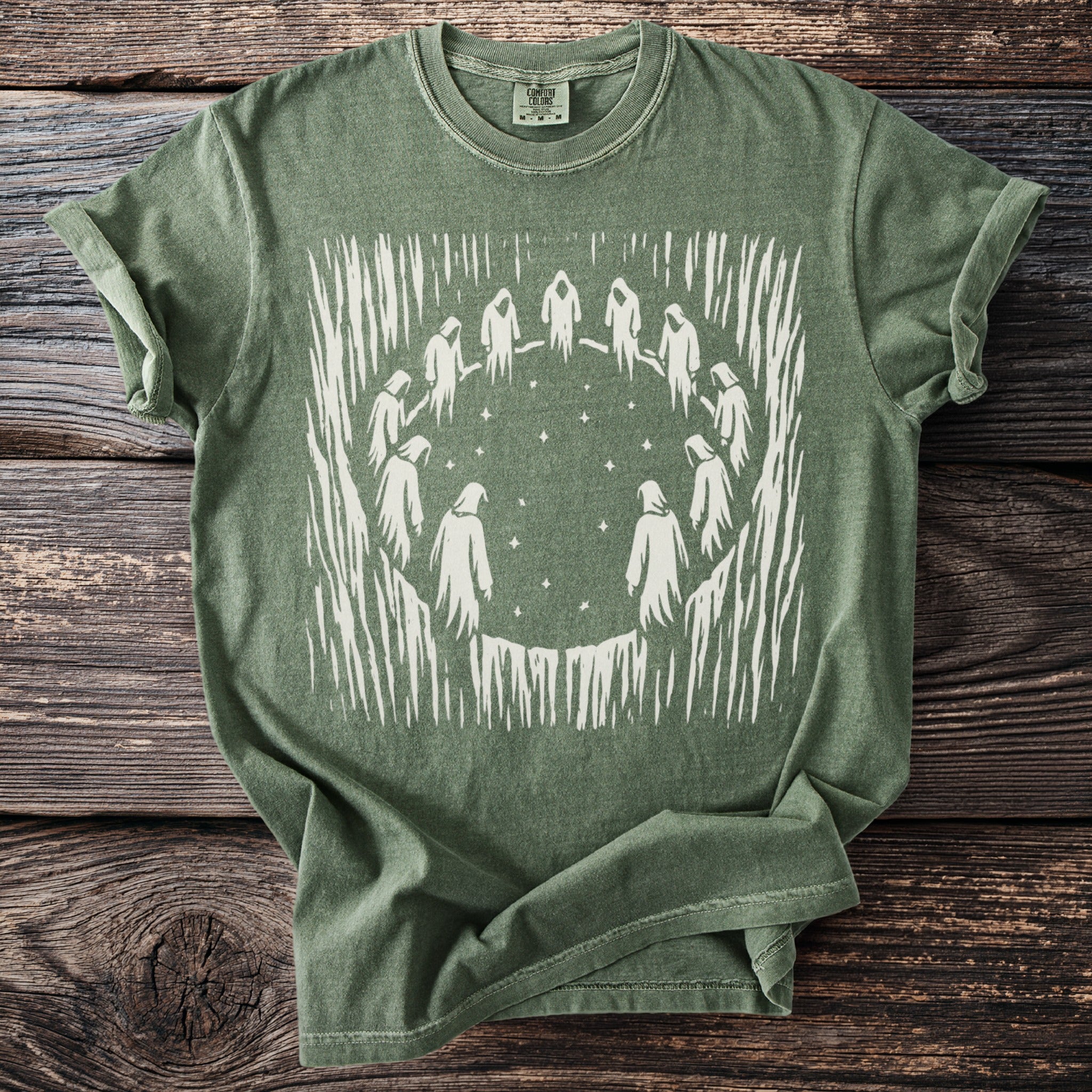 Green t-shirt with a graphic of figures in a circle under stars.