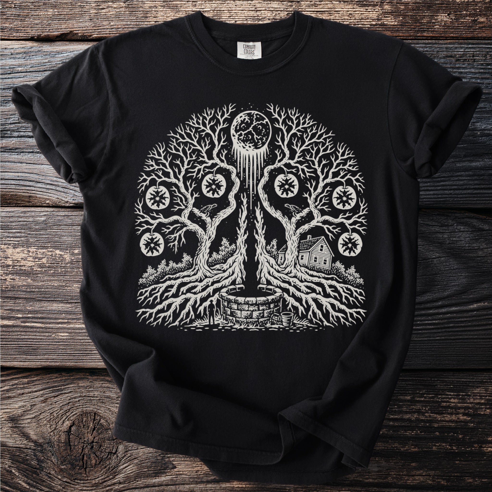 Black t-shirt with a white graphic of a moon, tree, well, house, and celestial fruit.