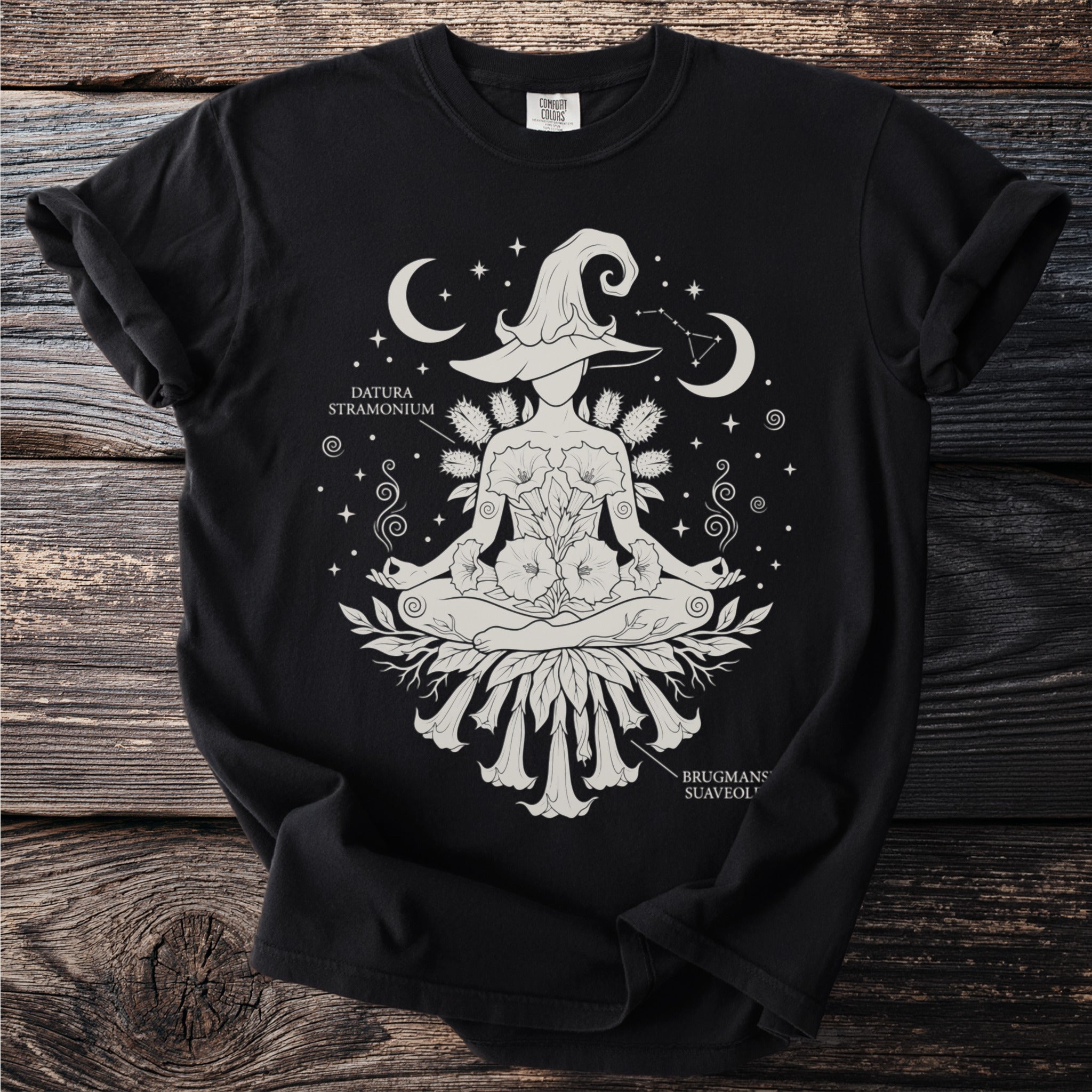 Black t-shirt with a white graphic of a meditating witch surrounded by flowers and celestial bodies.