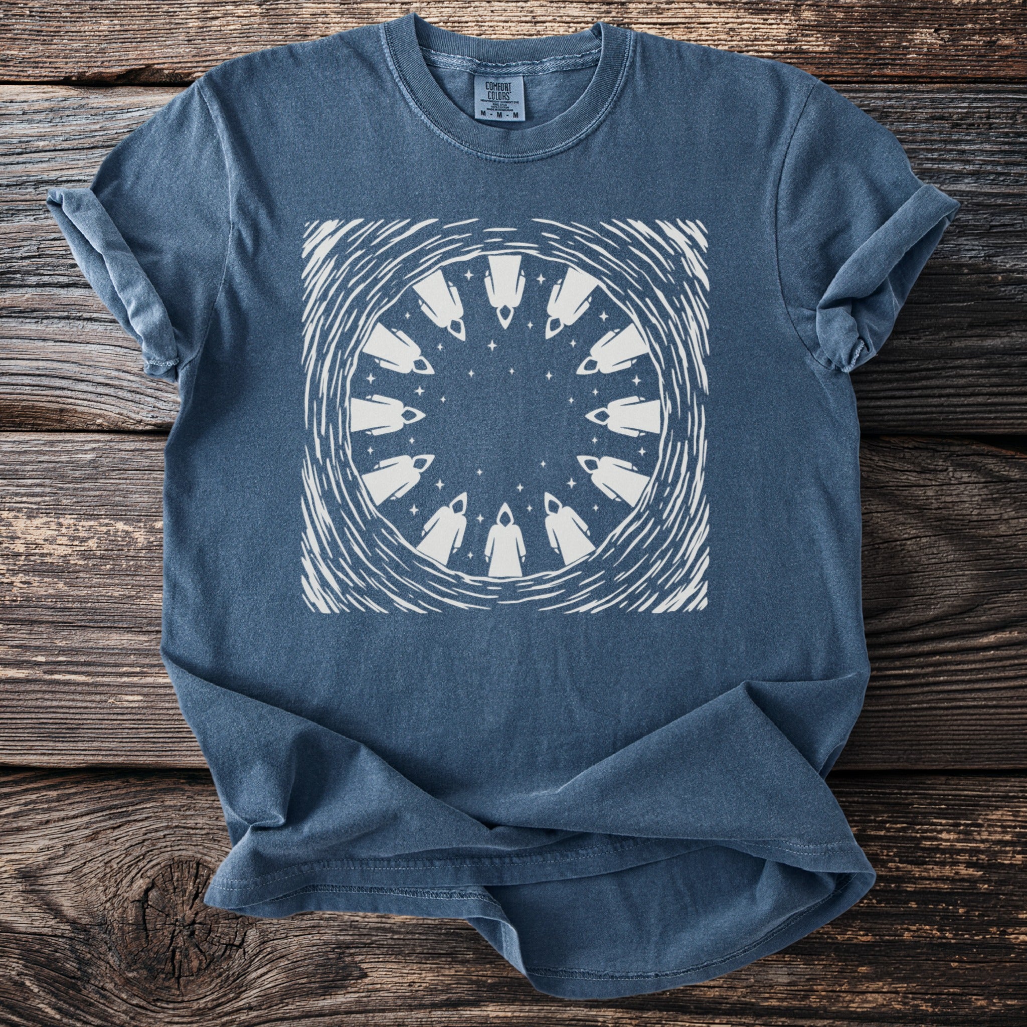 Blue t-shirt with white circular design of cloaked figures and stars.