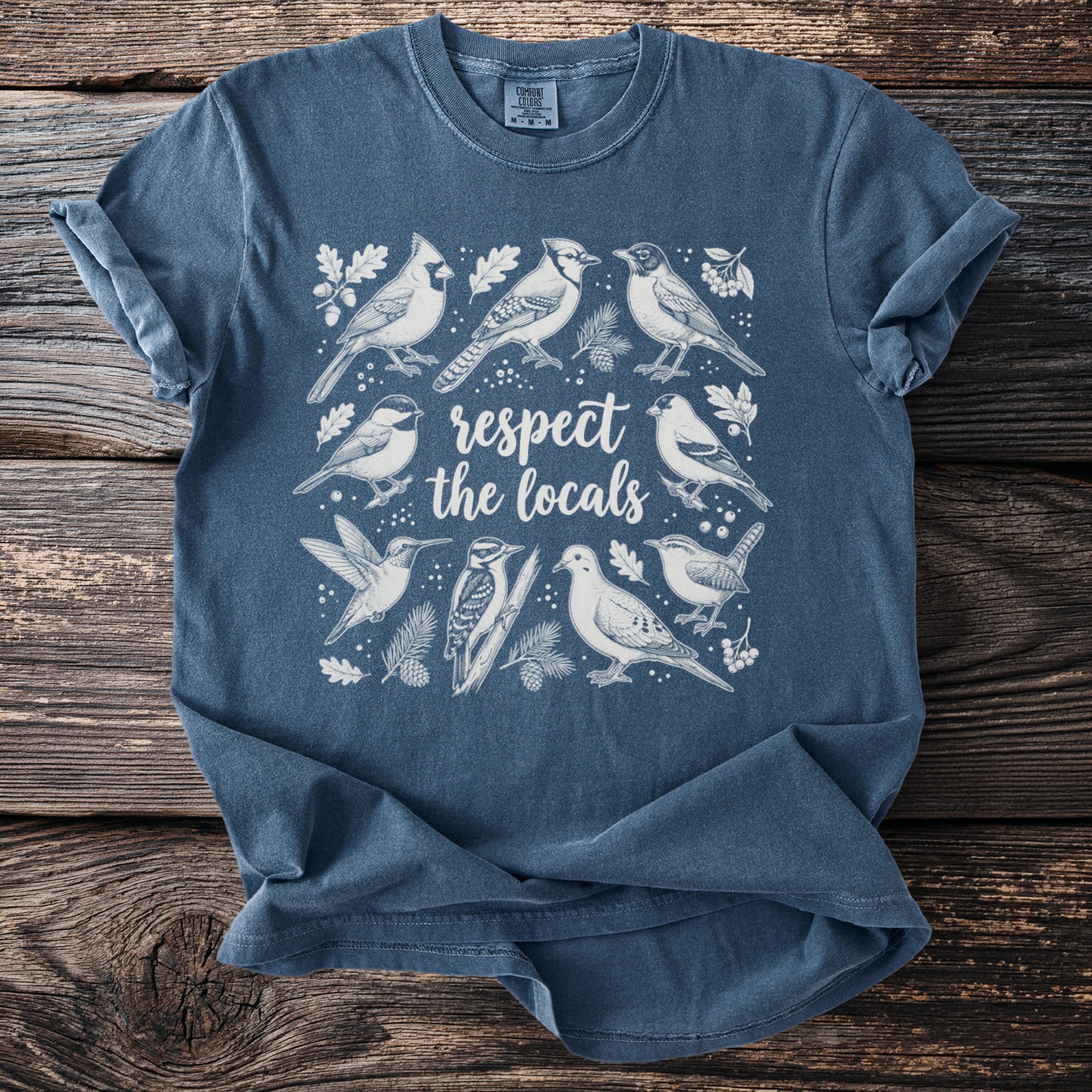 Blue t-shirt with white line art illustration of various birds and text "respect the locals".