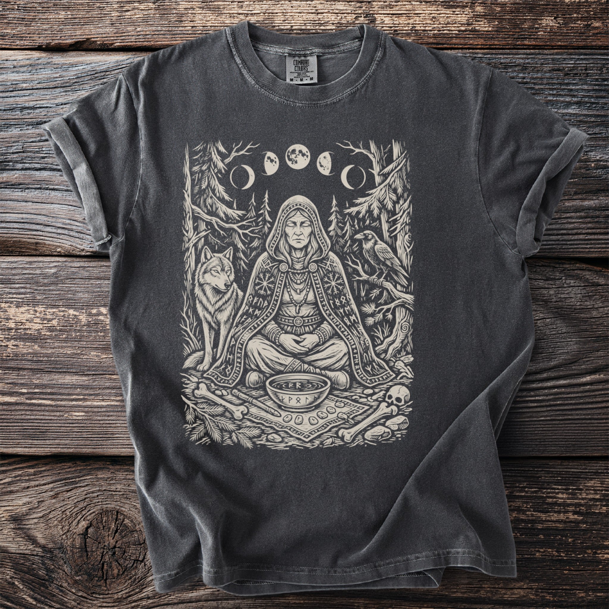 T-shirt with a dark gray print of a hooded figure surrounded by a wolf, raven, and runes.