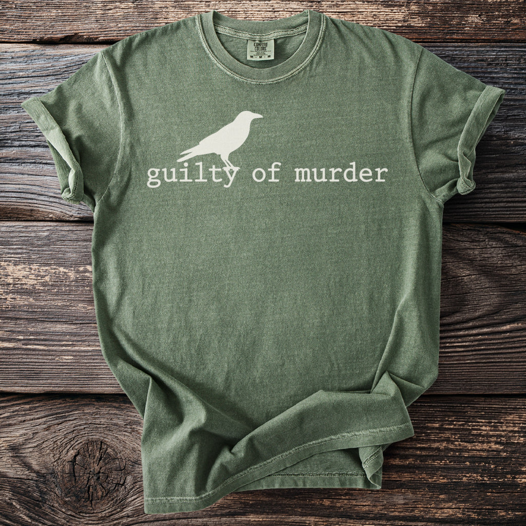 Green t-shirt with white crow graphic and text "guilty of murder."