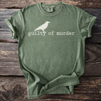 Green t-shirt with white crow graphic and text "guilty of murder."