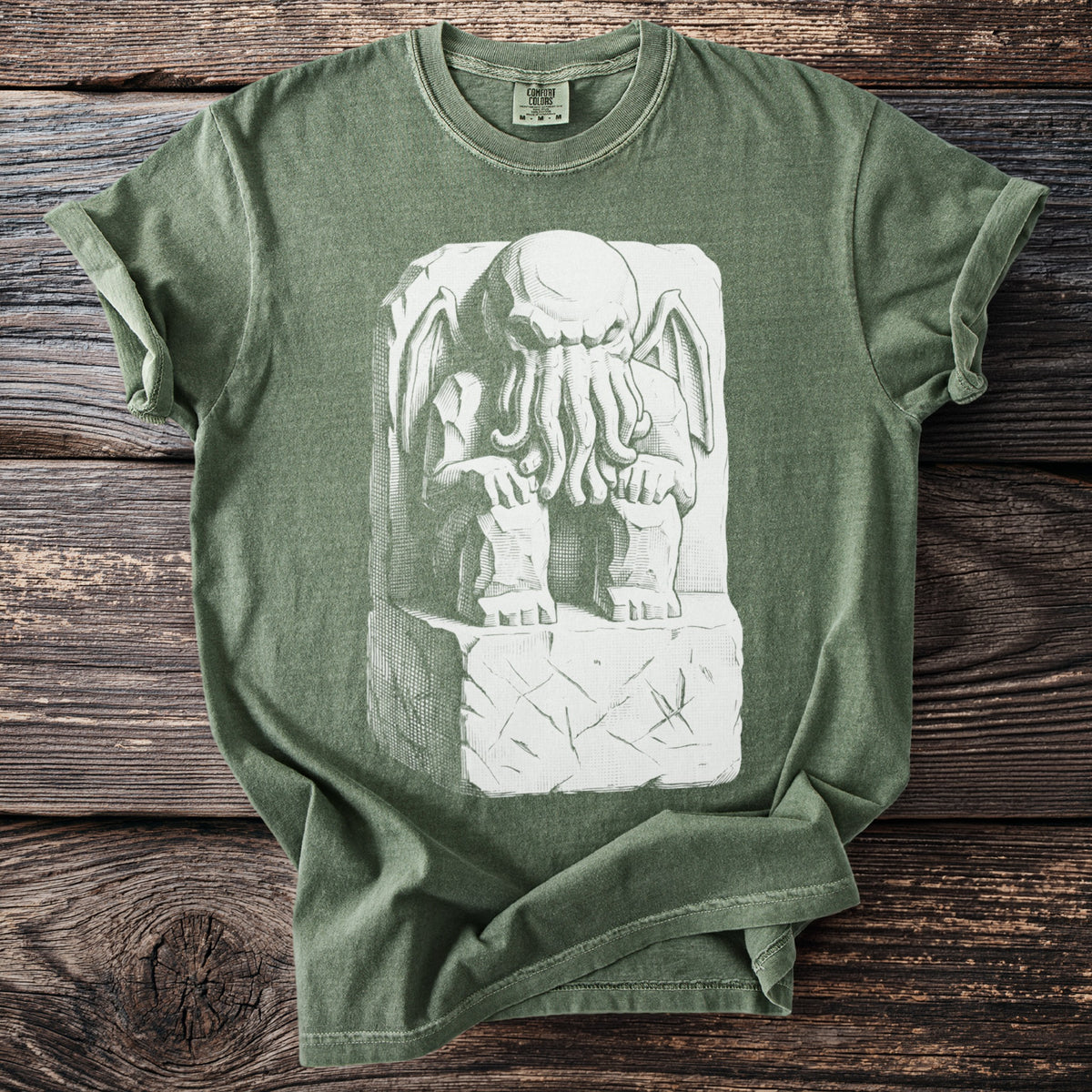 Green t-shirt with white tentacled creature seated on a stone block graphic.