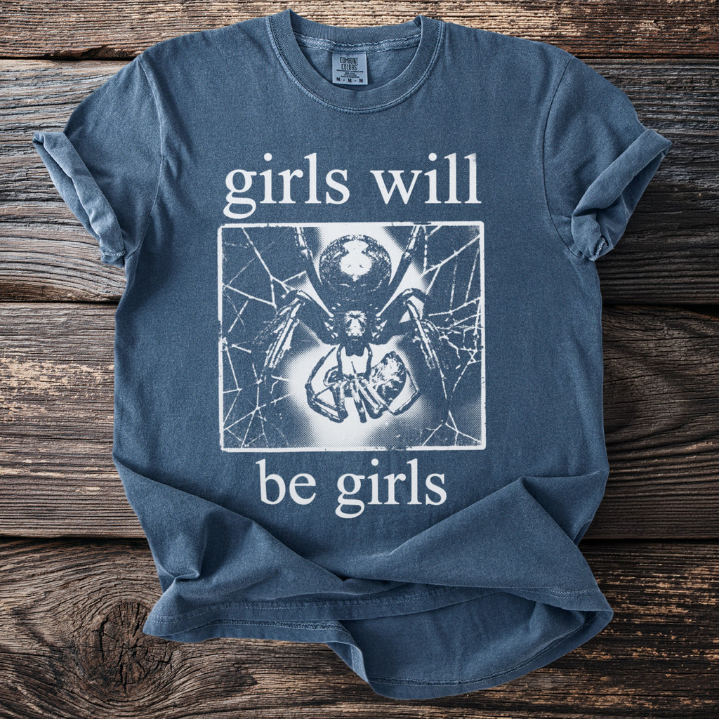 Blue t-shirt with white text "girls will be girls" and a spider graphic.