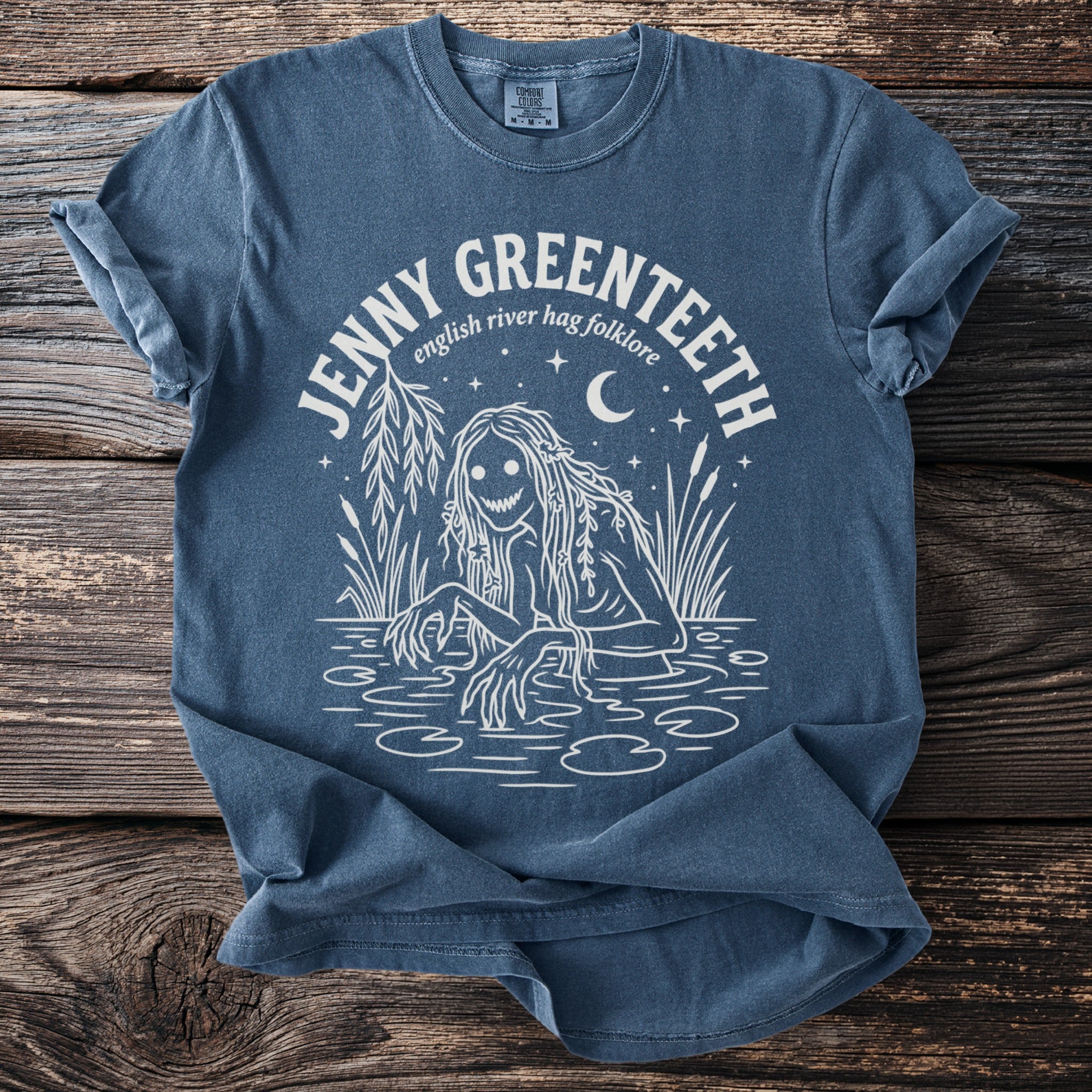 Blue t-shirt with white graphic of a swamp creature and text "JENNY GREENTEETH english river hag folklore".