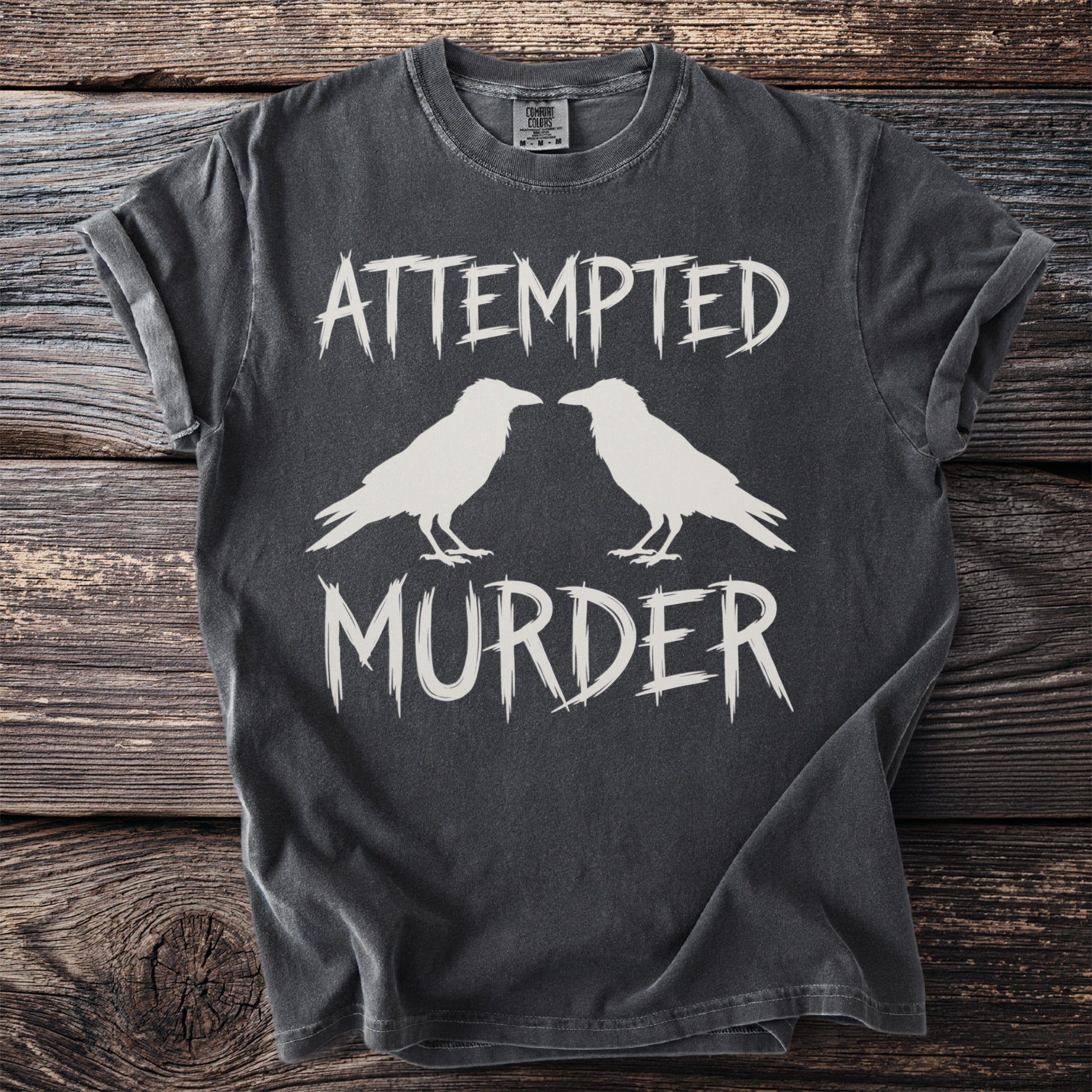 Dark t-shirt with white text "ATTEMPTED MURDER" and two white ravens.