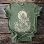 Green t-shirt with a cream print of a winged figure in a chariot pulled by cats.