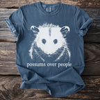 Blue t-shirt with white graphic of a possum and text "possums over people."