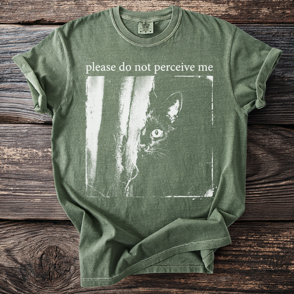 Green t-shirt with a black cat peeking from behind a vertical line and text "please do not perceive me".