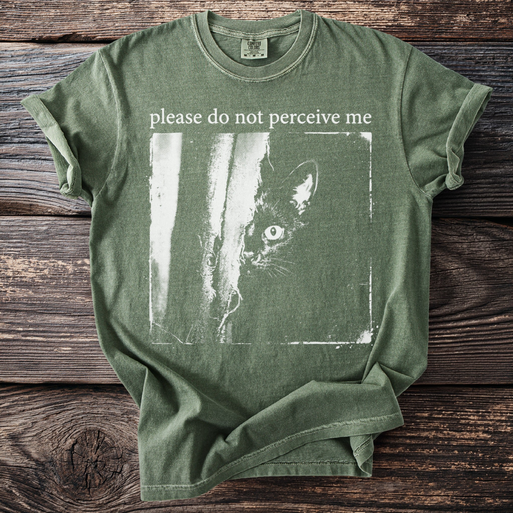 Green t-shirt with a black cat peeking from behind a vertical line and text "please do not perceive me".