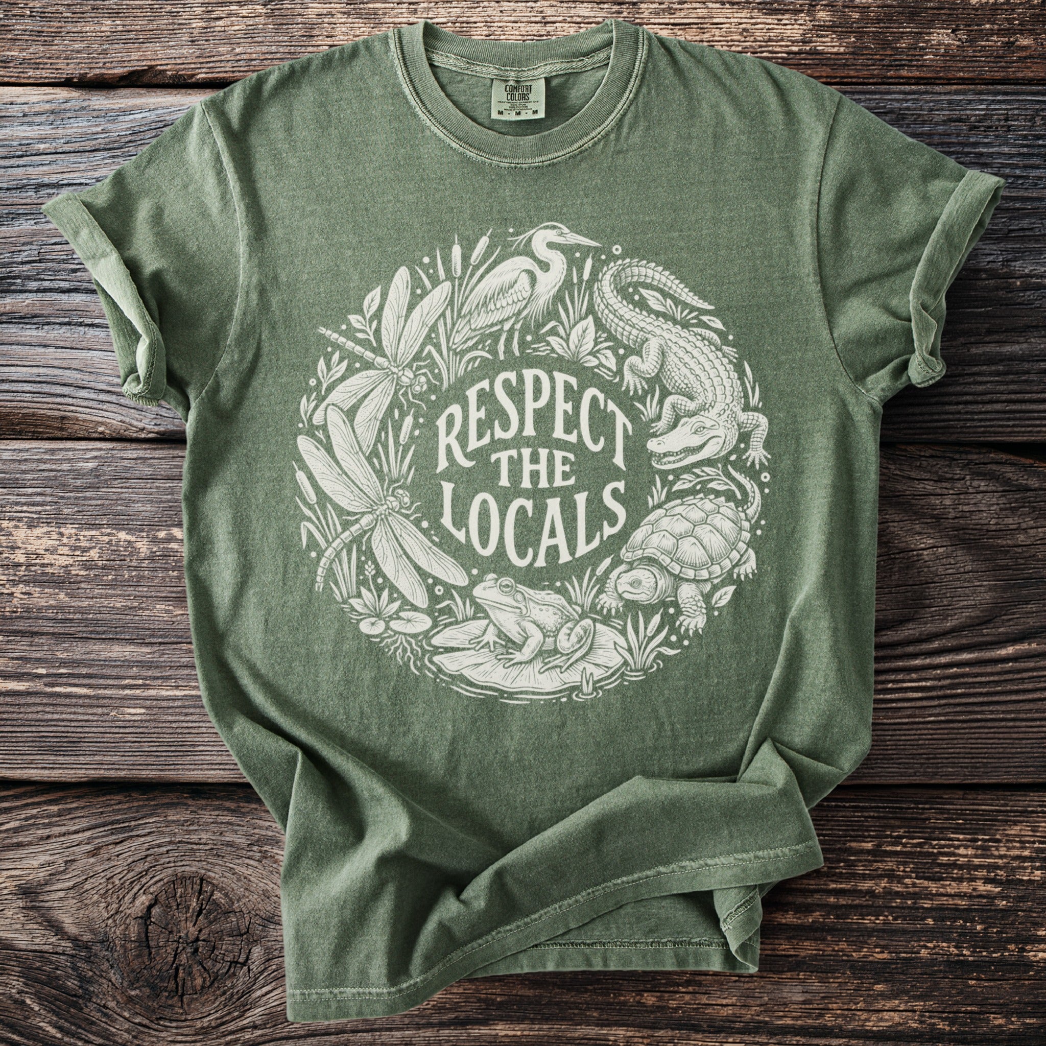 Green t-shirt with white circle graphic of local wildlife and text "Respect the Locals."