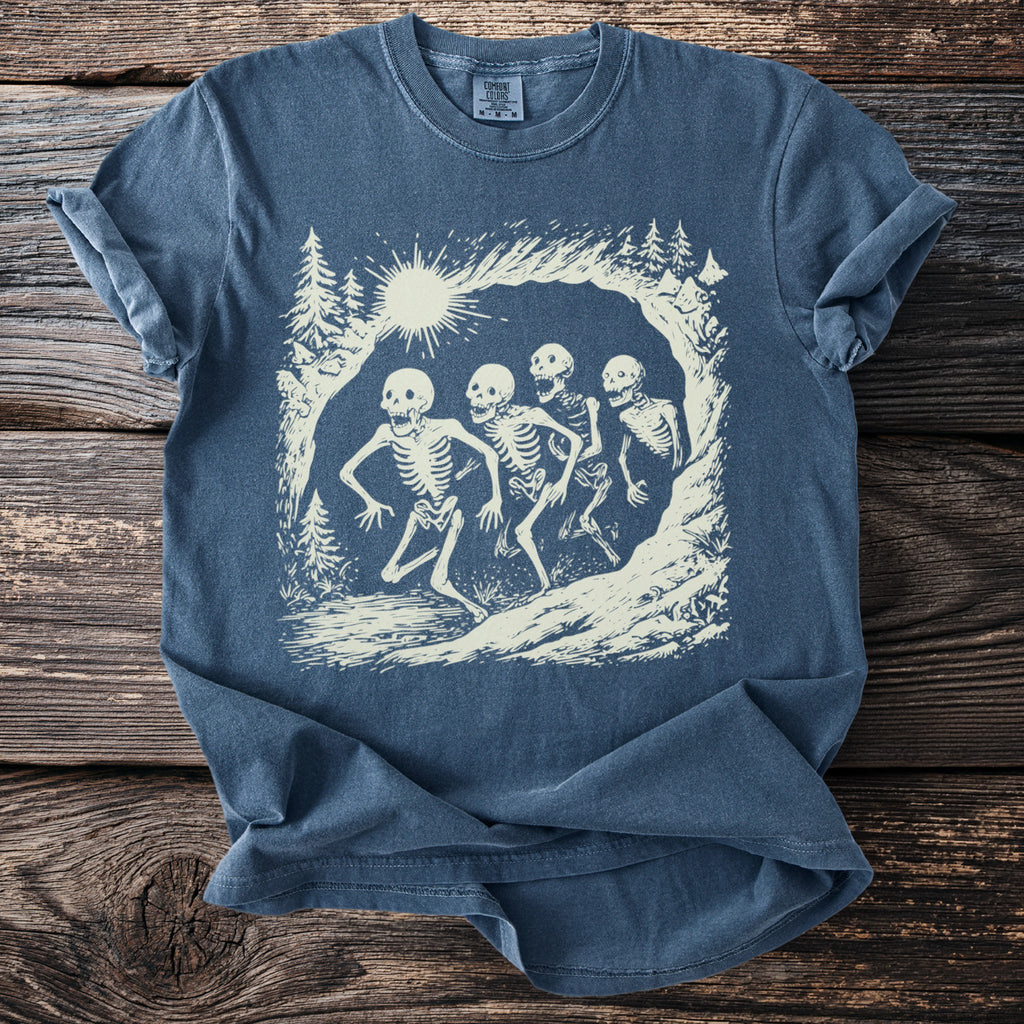 Blue t-shirt with a graphic of four skeletons running in a forest landscape.