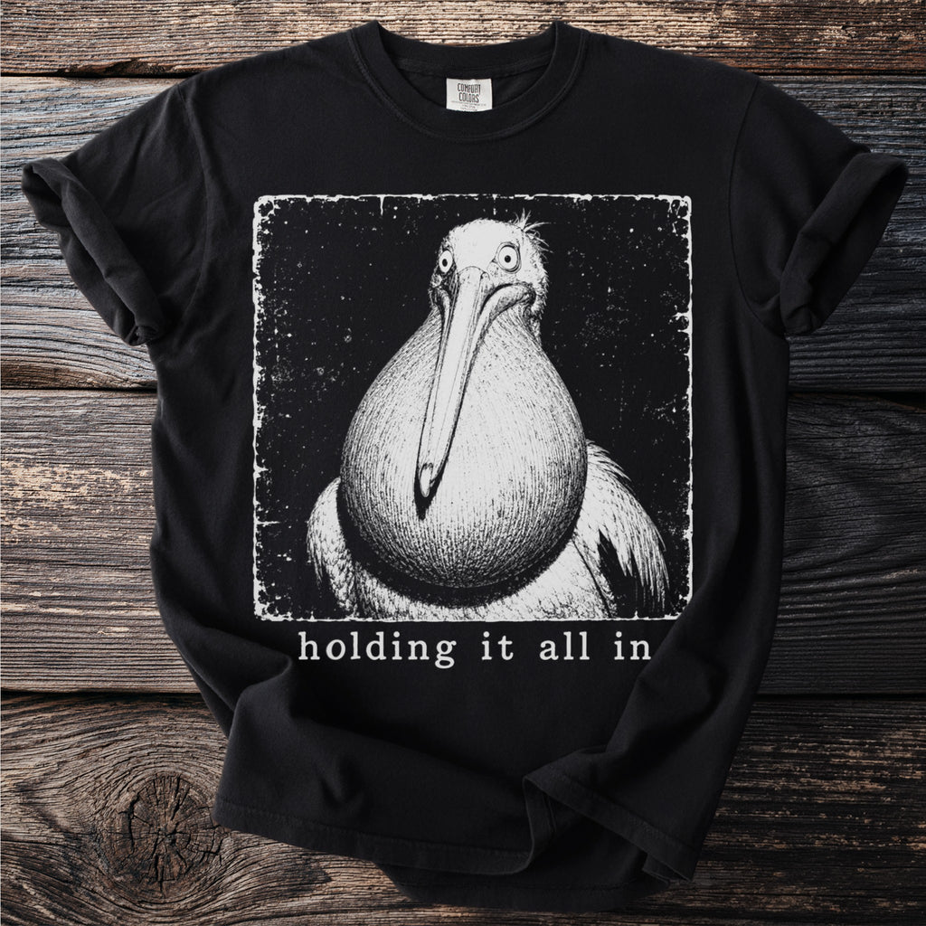 Black t-shirt with a distressed print of a pelican and text "holding it all in".