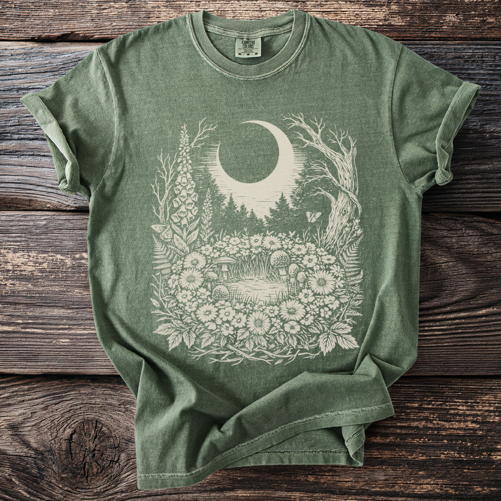 Green t-shirt with a cream moon, forest, and floral design.