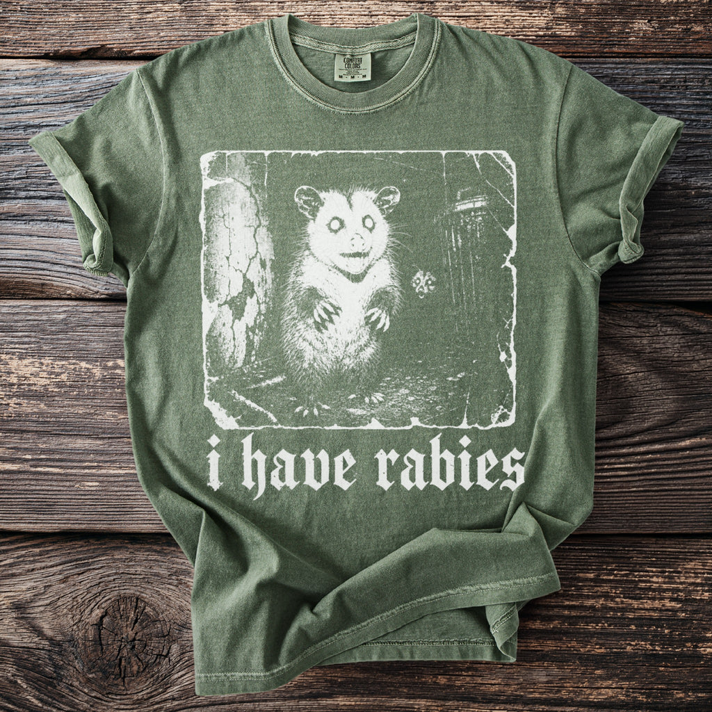 Green t-shirt with a distressed graphic of a possum and text that reads "i have rabies".