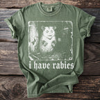Green t-shirt with a distressed graphic of a possum and text that reads "i have rabies".