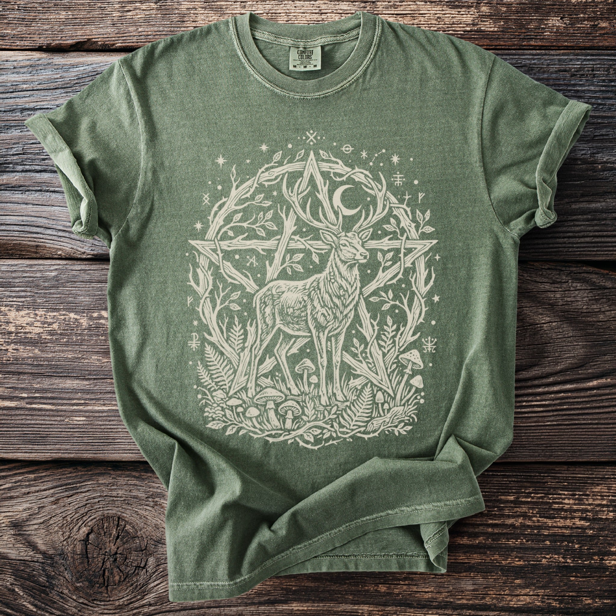 Green t-shirt with a white illustration of a deer and a pentagram surrounded by nature elements.