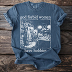 Blue t-shirt with text "god forbid women have hobbies" and vintage drawing.