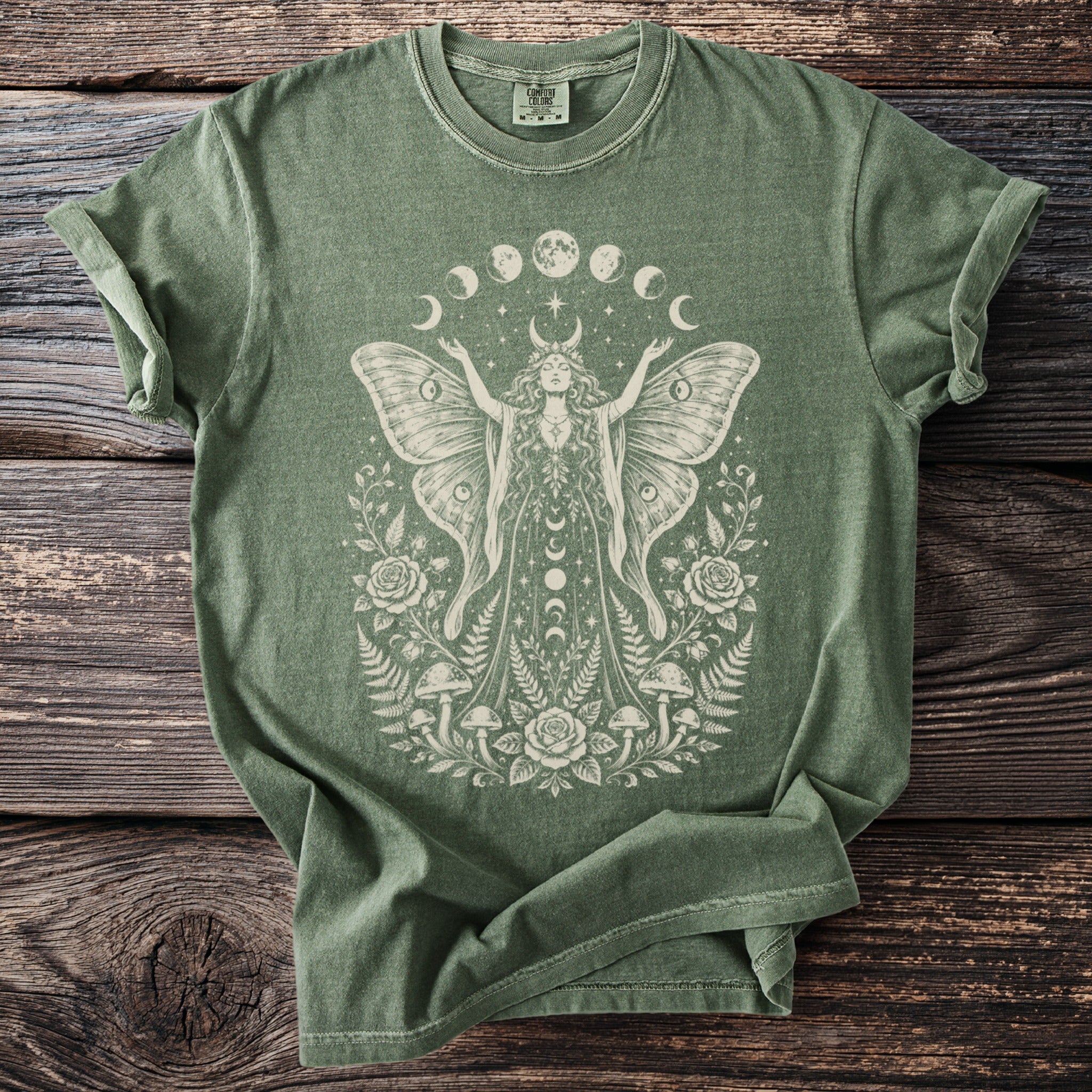 Green t-shirt with a cream moth woman, moon phases, roses, mushrooms, and ferns design.