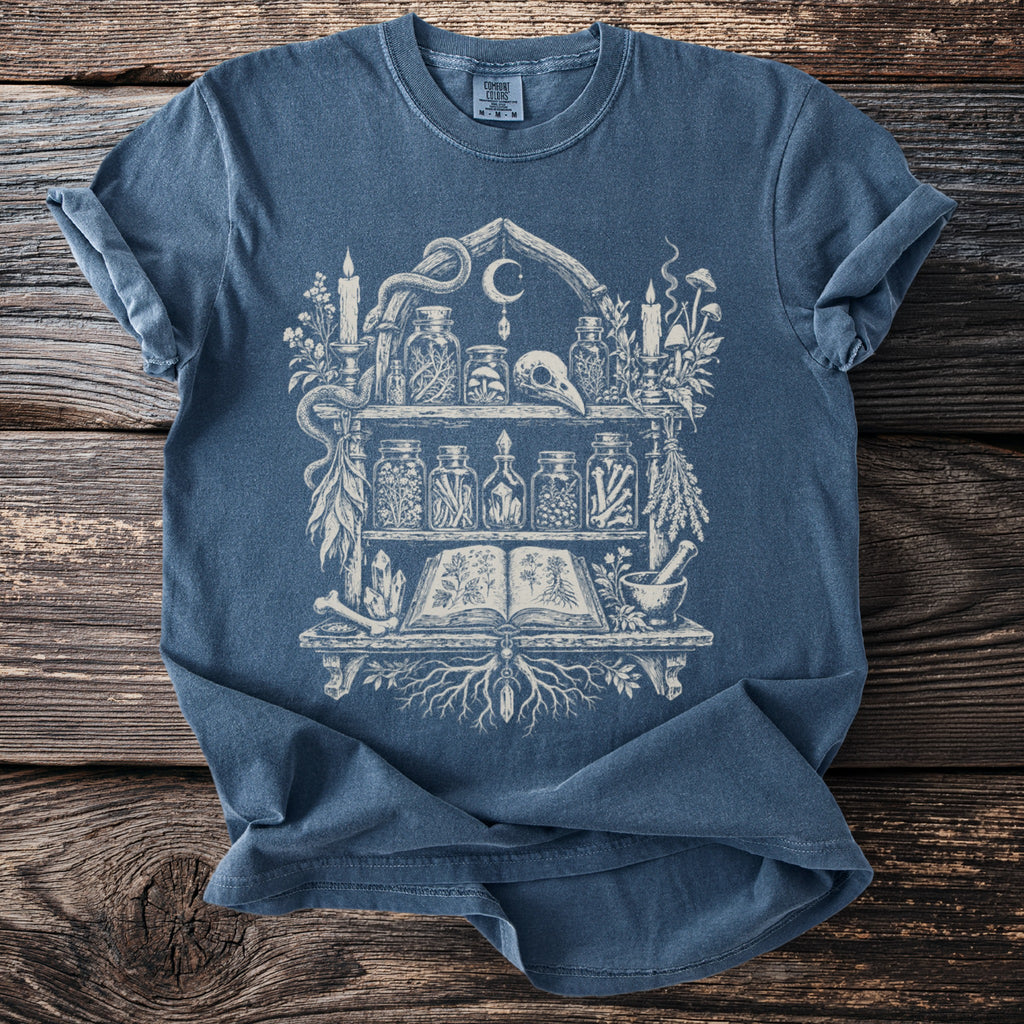 Blue Comfort Colors t-shirt with a white occult shelf graphic featuring a skull and jars.