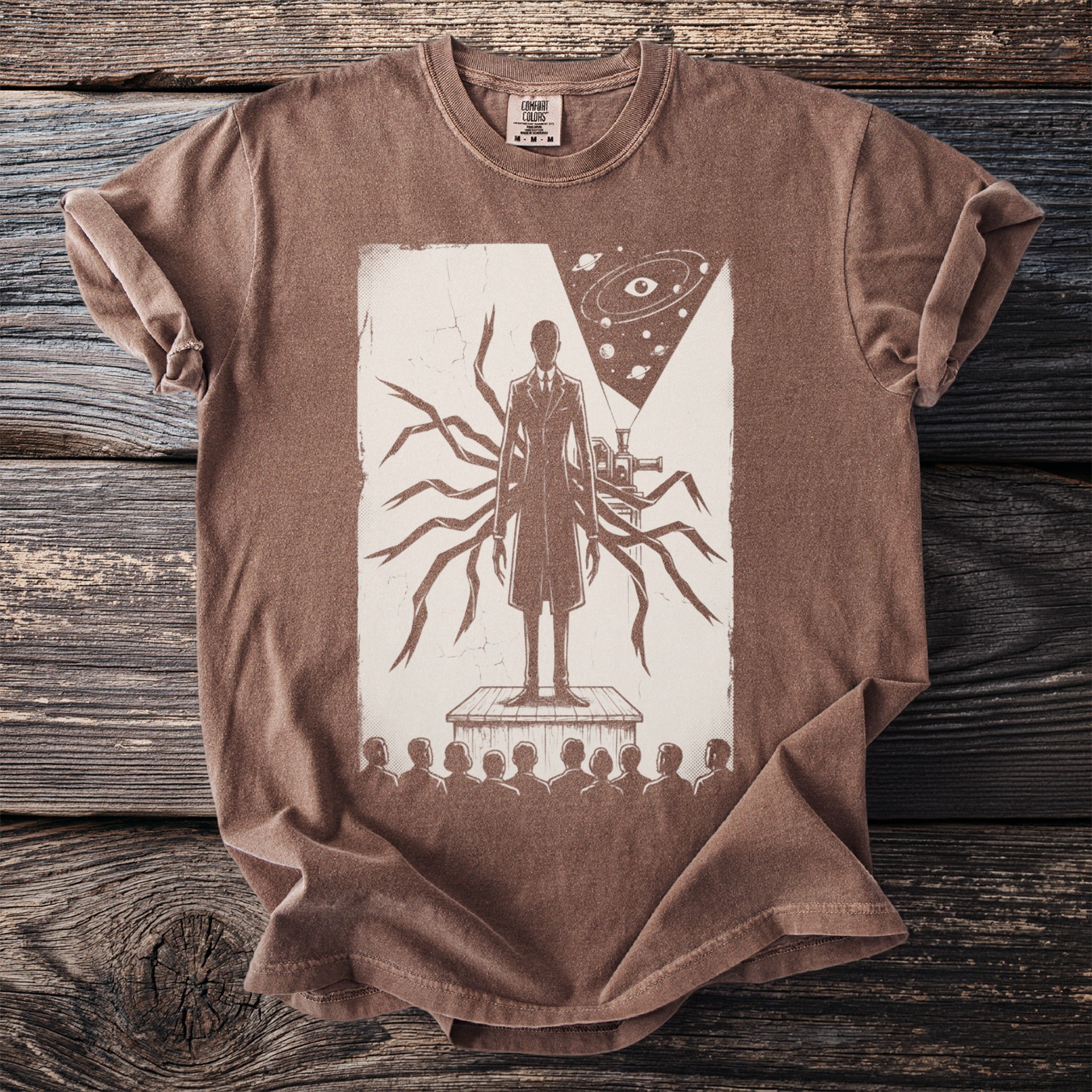 Brown t-shirt with a print of a figure with many arms, a telescope, and an eye in space.