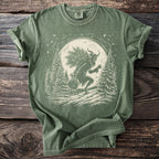 Green t-shirt with a Krampus illustration carrying a sack and branches under a moon.