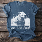Capybara in hot spring graphic with "zen but feral" text on a blue t-shirt.