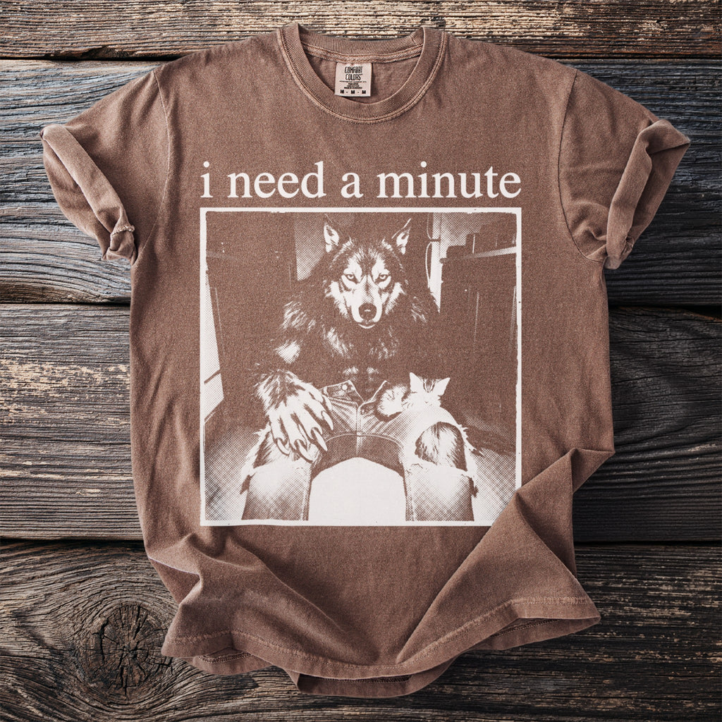 Brown t-shirt with "i need a minute" text and a werewolf holding a cat graphic.