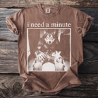 Brown t-shirt with "i need a minute" text and a werewolf holding a cat graphic.