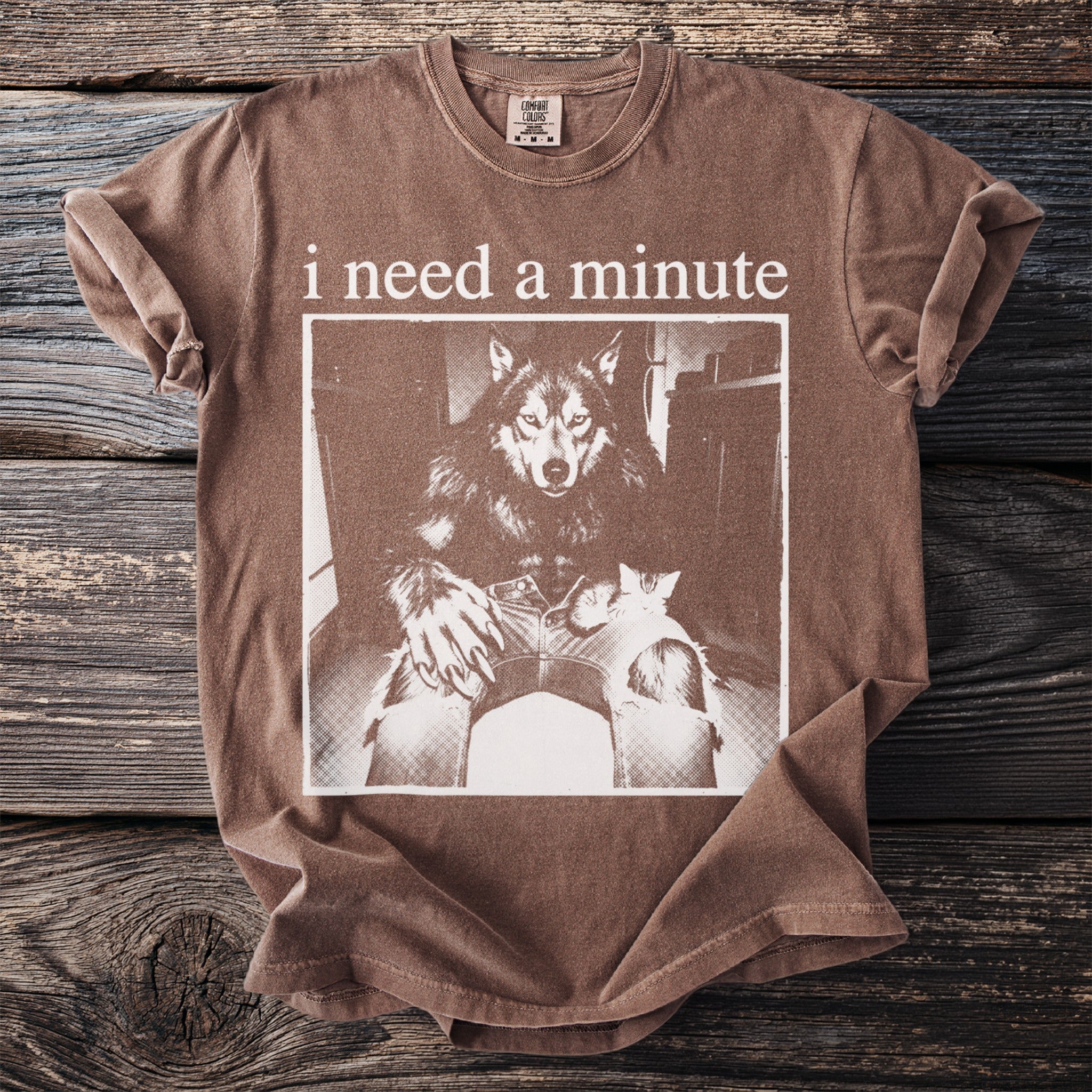 Brown t-shirt with "i need a minute" text and a werewolf holding a cat graphic.