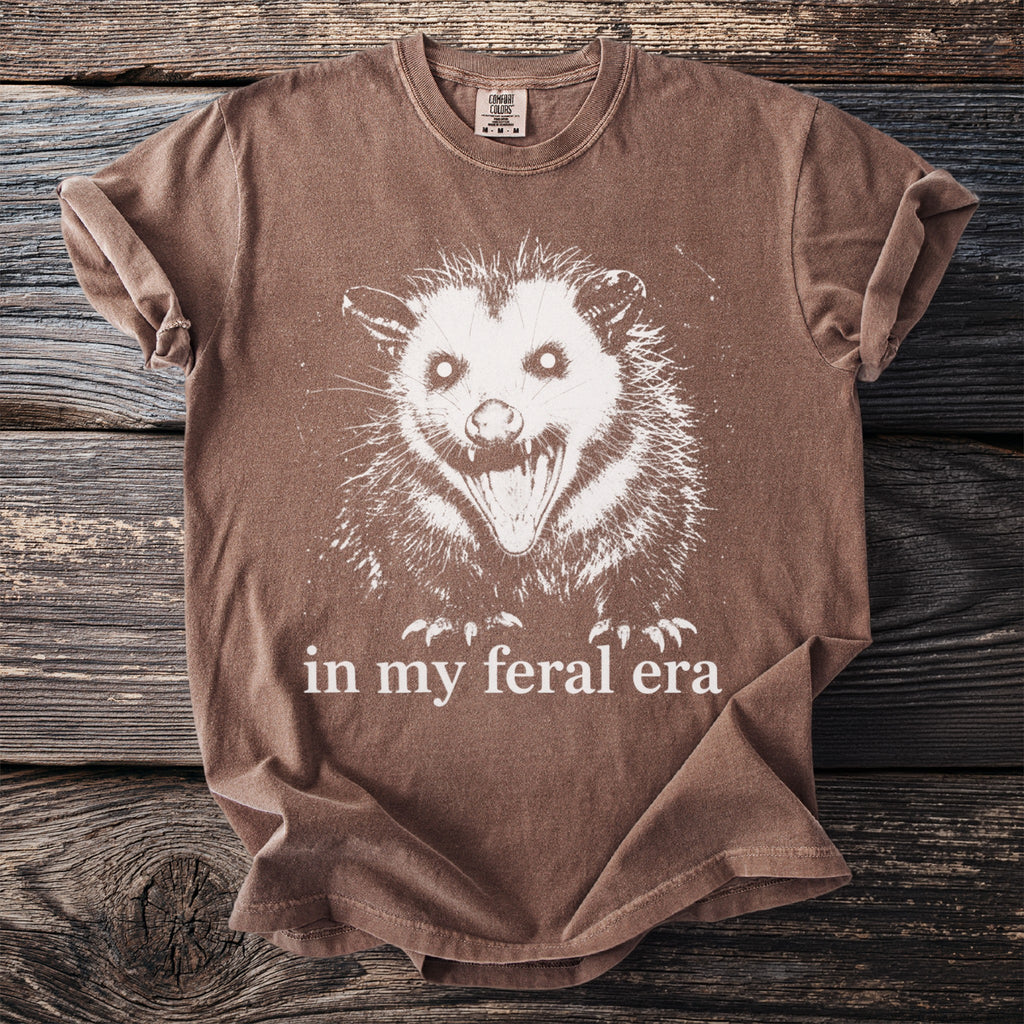 Brown t-shirt with white feral opossum graphic and text "in my feral era."