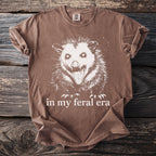 Brown t-shirt with white feral opossum graphic and text "in my feral era."