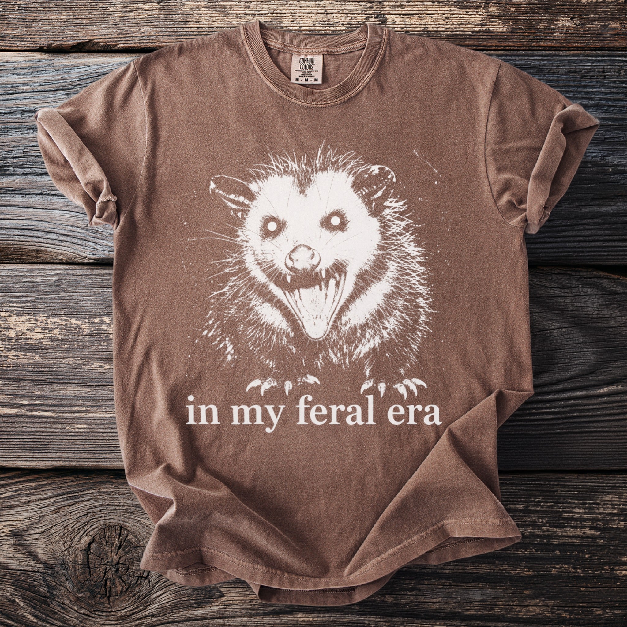 Brown t-shirt with white feral opossum graphic and text "in my feral era."