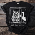 Black t-shirt with a graphic of a raccoon in a cage holding a spoon and a goose.