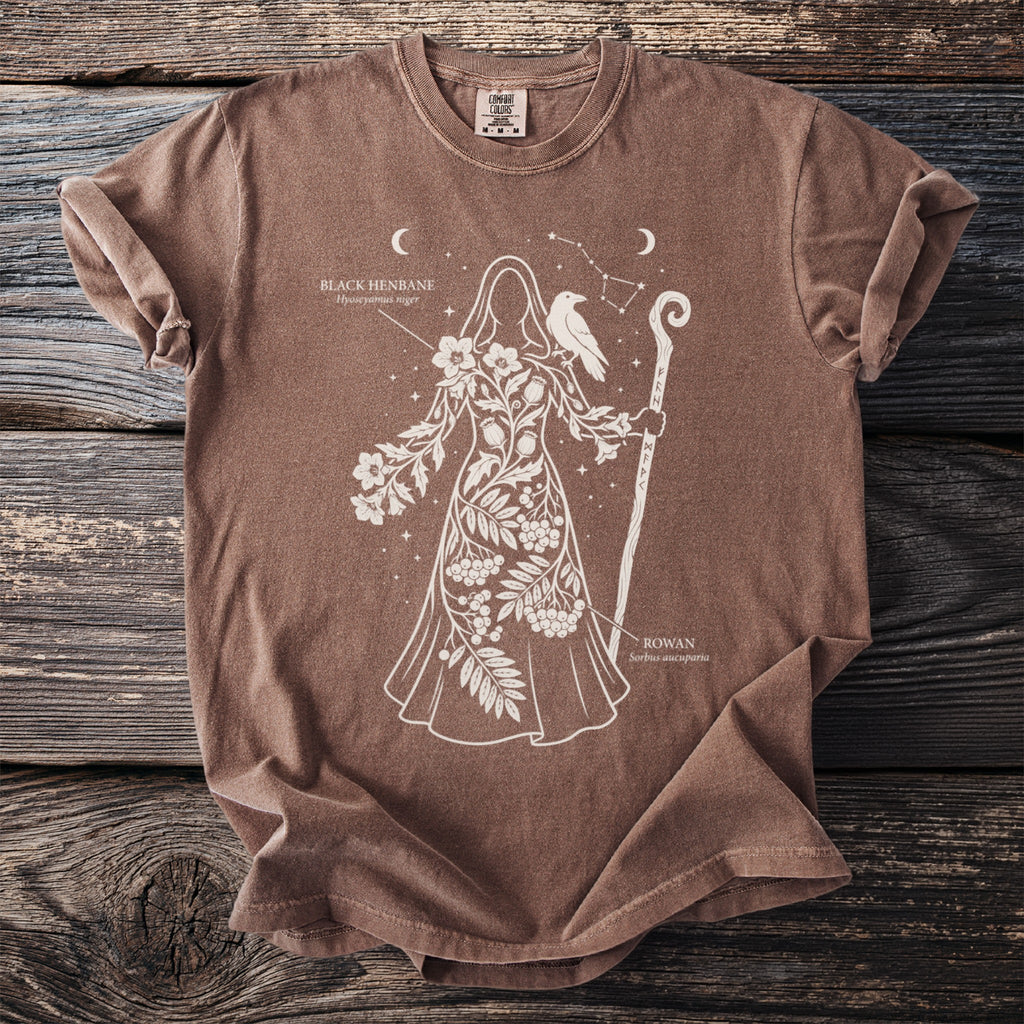 Brown t-shirt featuring a woman with flowers, a raven, and runes. Includes text "Black Henbane" and "Rowan".