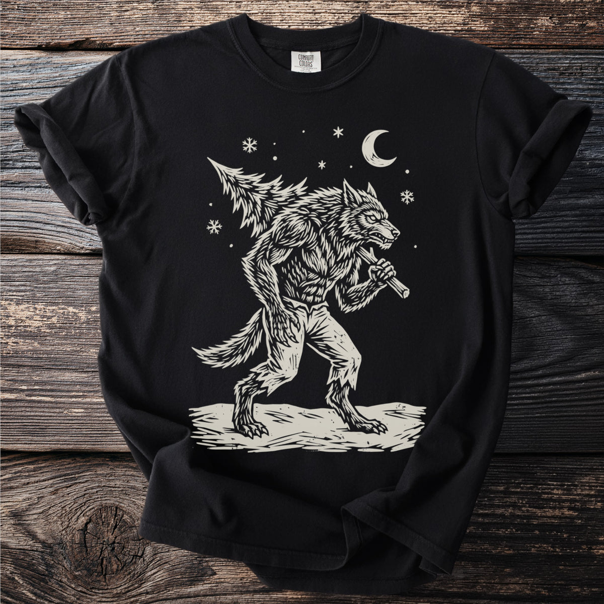 Black t-shirt with a cream folk-cut print: a snarling werewolf in torn trousers walks through the snow with a fir tree over his shoulder.
