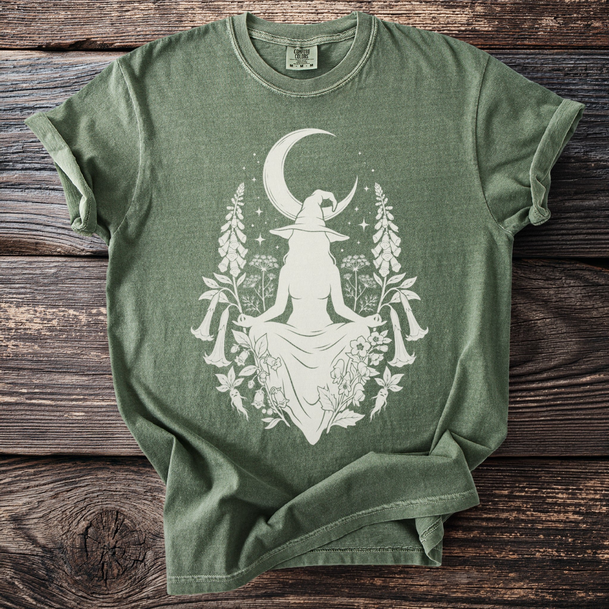 Green t-shirt with white graphic of a witch, moon, and botanical elements.