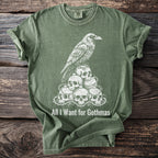 Green t-shirt with a white raven on skulls graphic and text "All I Want for Gothmas".