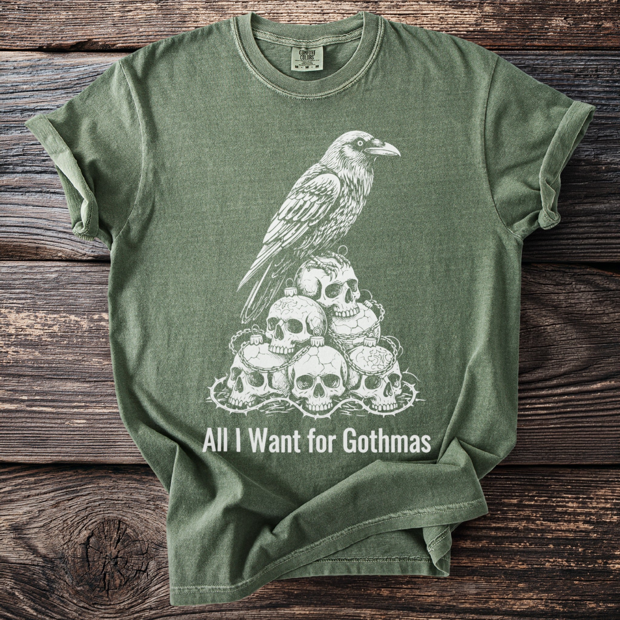 Green t-shirt with a white raven on skulls graphic and text "All I Want for Gothmas".